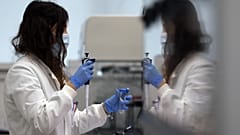 مساعدة مختبر تستخدم الماصّة لتحضير RNA لفيروس كورونا من أجل التسلسل الجيني في معهد ويلكوم سانجر الذي تديره أبحاث الجينوم في كامبريدج