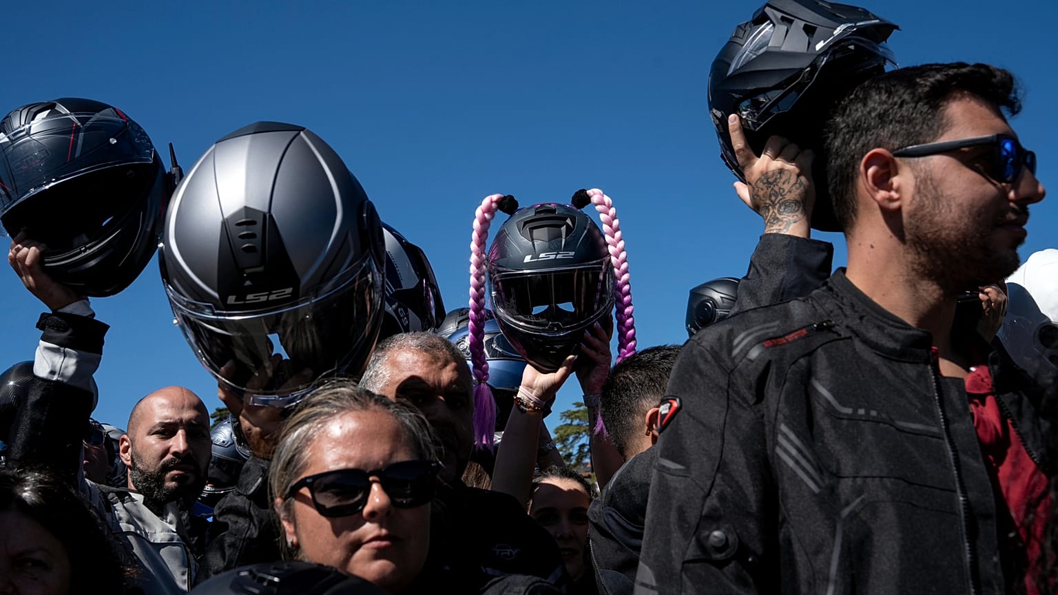 Motorcyclists hold up their helmets to be blessed during the 10th Pilgrimage of the Blessing of Helmets