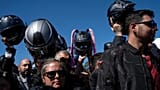 Motorcyclists hold up their helmets to be blessed during the 10th Pilgrimage of the Blessing of Helmets