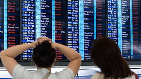 Passengers look at an information display board showing cancelled flights due to the Super Typhoon Ragasa, at the Hong Kong International Airport.