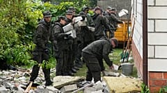 Beamte der Territorialen Verteidigung räumen Trümmer vom zerstörten Dach eines Hauses auf, nachdem mehrere russische Drohnen das Haus in Wyryki in der Nähe von Lublin, Polen, getroffen haben, Donnerstag, 11. September 2025