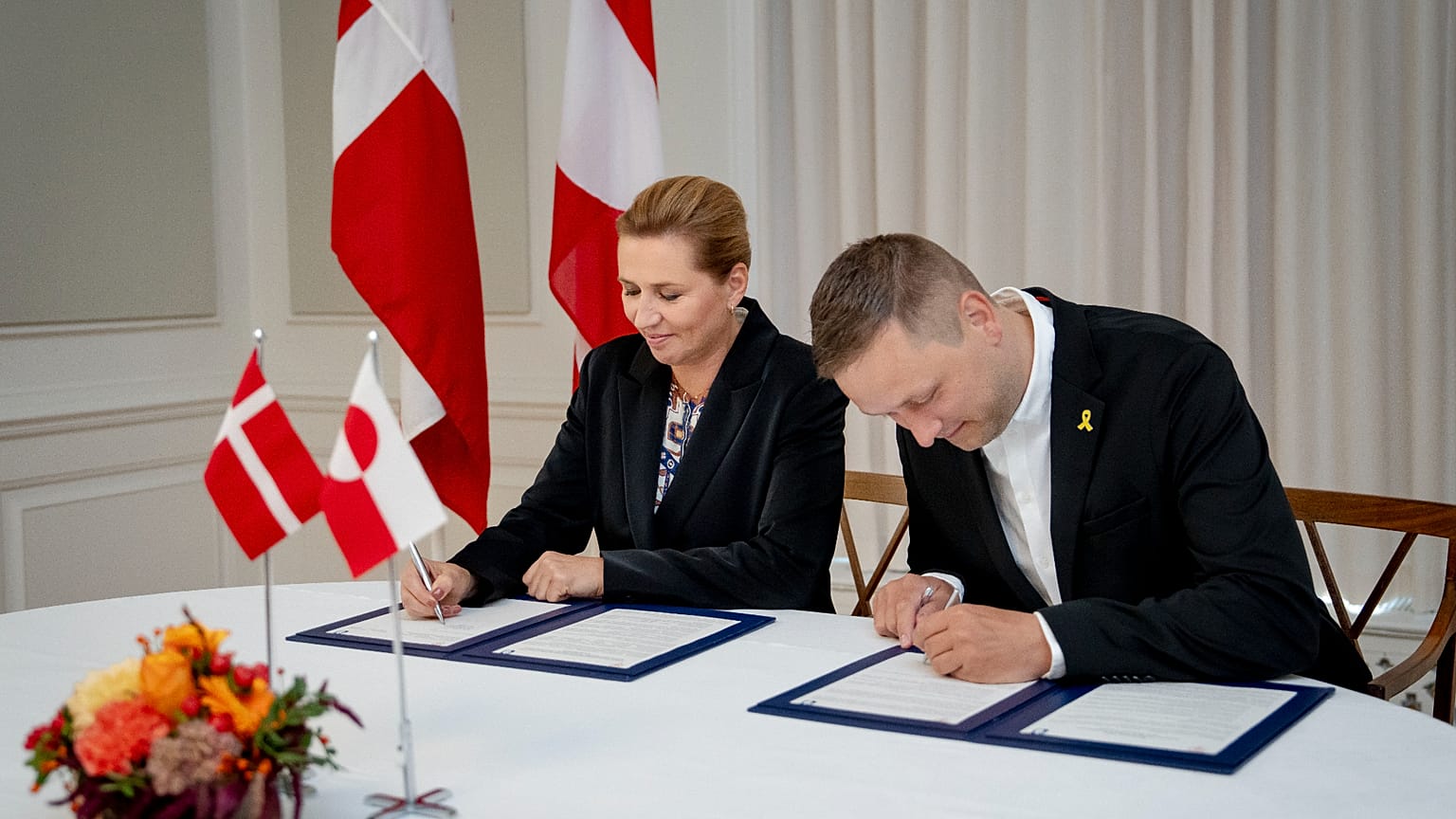 Denmark's Prime Minister Mette Frederiksen, left, and Greenland's government leader, Jens-Frederik Nielsen, right, sign a framework agreement for a self-sustaining Greenland.