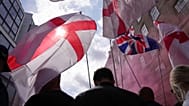 FILE: Demonstrators carry England and Union Jack flags during a Tommy Robinson-led Unite the Kingdom march and rally in London, Saturday Sept. 13, 2025