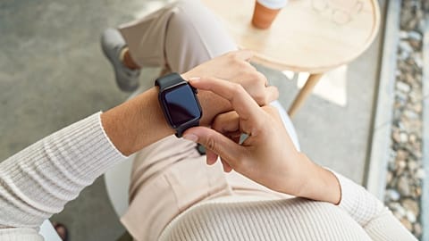A woman adjusts her smartwatch.