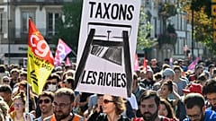 Un manifestant tient une pancarte sur laquelle on peut lire "taxons les riches" lors d'un rassemblement du mouvement "Bloquons tout" à Strasbourg, dans l'est de la France.