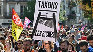 A protester holds a placard that reads, "let's tax the rich," during a rally of the "Block Everything" movement in Strasbourg, eastern France