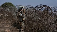 Um soldado da paz francês da FINUL olha através de binóculos enquanto se encontra numa colina com vista para Kfar Kila, 20 de agosto de 2025