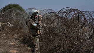 A French UNIFIL peacekeeper looks through binoculars while standing on a hill overlooking Kfar Kila, 20 August, 2025