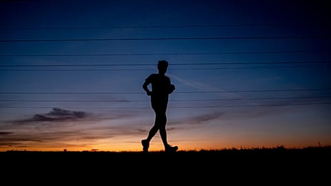 A man runs on a small road in the outskirts of Frankfurt, Germany, before sunrise on Sept. 8, 2020.