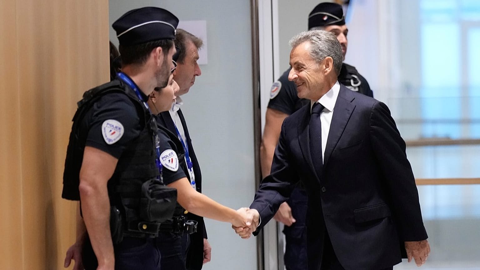 Former French President Nicolas Sarkozy shakes hands with a police officer before his verdict in Paris, 25 September 2025