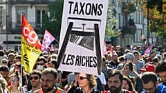 A protester holds a placard that reads, "tax the rich," during a rally in Strasbourg, 10 September, 2025