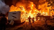 Residents work to stop flames from a burning home from spreading to a neighboring house as the 6-5 Fire burns through the Chinese Camp community of Tuolumne County, Calif.