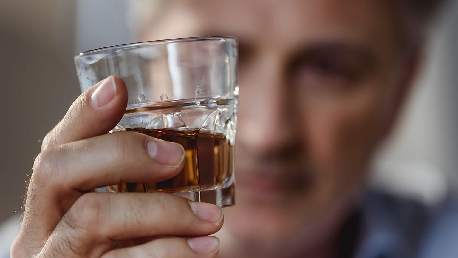 Ein Mann betrachtet ein Glas Whisky.