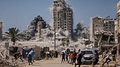 فلسطينيون يركضون للاحتماء خلال غارة إسرائيلية استهدفت مبنى مرتفعًا في مدينة غزة، الجمعة 5 أيلول/ سبتمبر 2025، عقب تحذير من الجيش الإسرائيلي.
