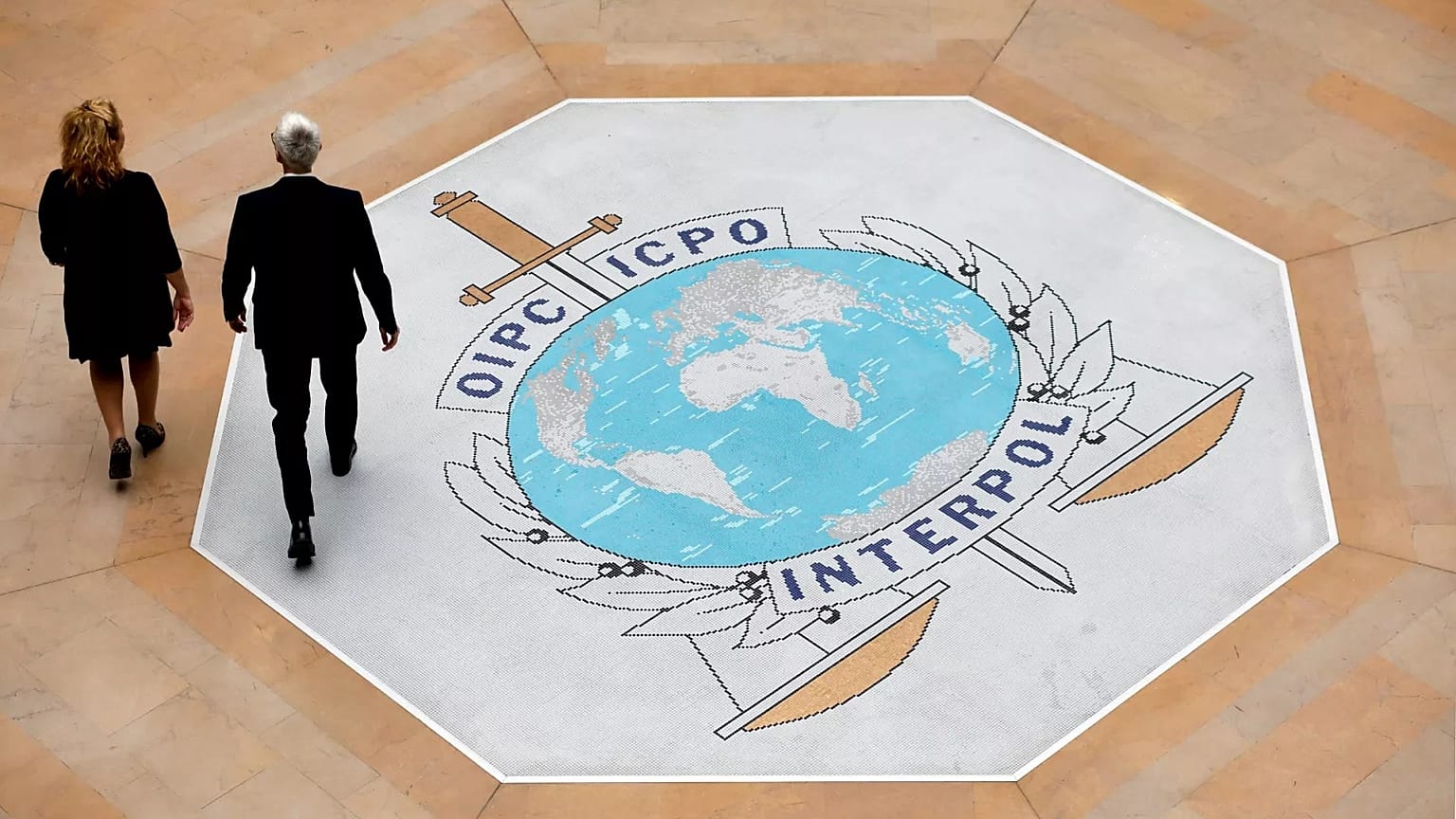 Dos personas caminan sobre el logotipo de Interpol en la sede de la agencia internacional de la Policía en Lyon, 8 de noviembre de 2018.