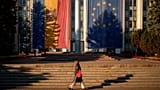 Una donna cammina davanti al palazzo del governo, decorato con le bandiere dell'Unione Europea e della Moldavia a Chișinău, 26 settembre 2025