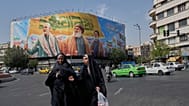 Two women walk past huge banner showing the late IRGC commander Qassem Soleimani and Hezbollah's Hassan Nasrallah and Hashem Safieddine, Tehran, Iran, Saturday, Sept. 27, 2025