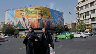 Two women walk past huge banner showing the late IRGC commander Qassem Soleimani and Hezbollah's Hassan Nasrallah and Hashem Safieddine, Tehran, Iran, Saturday, Sept. 27, 2025
