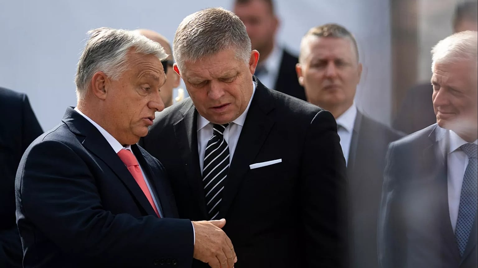 O primeiro-ministro húngaro, Viktor Orban, à esquerda, e o seu homólogo eslovaco, Robert Fico, falam um com o outro antes de proferirem os seus discursos durante a celebração do 130º aniversário da
