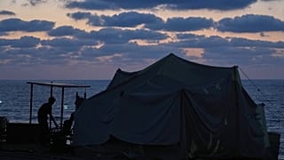 فلسطيني نازح يقف بجانب خيمة نُصبت على الواجهة البحرية في مخيم النصيرات وسط قطاع غزة، الجمعة 26 أيلول/سبتمبر 2025. 