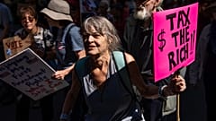 Una mujer con un cartel que dice "Impuestos a los ricos" marcha por Manhattan, el sábado 20 de septiembre de 2025, en Nueva York.