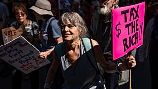 Una mujer con un cartel que dice "Impuestos a los ricos" marcha por Manhattan, el sábado 20 de septiembre de 2025, en Nueva York.
