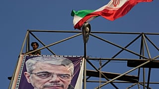 FILE A worker posts a banner showing a portrait of Gen Mohammad Hossein Bagheri, who was killed in an Israeli strike in June, at Baharestan Square in Tehran, 22 September 2025