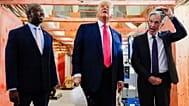 Jerome Powell, de la Fed, a la derecha, se quita el casco mientras el presidente Trump, en el centro, y el senador Tim Scott,  en Washington en 2025.