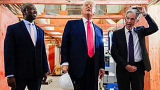 Jerome Powell, de la Fed, a la derecha, se quita el casco mientras el presidente Trump, en el centro, y el senador Tim Scott,  en Washington en 2025.