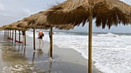 Foto de archivo: La gente camina por una playa desierta mientras las olas alcanzan las sombrillas de paja en Ibiza, España, el domingo 3 de septiembre de 2023. 
