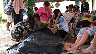 Personas rodean una bolsa para cadáveres en la ciudad de Bogo tras el seísmo del 30 de septiembre.