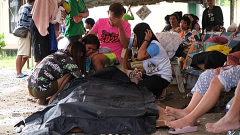 Personas rodean una bolsa para cadáveres en la ciudad de Bogo tras el seísmo del 30 de septiembre.