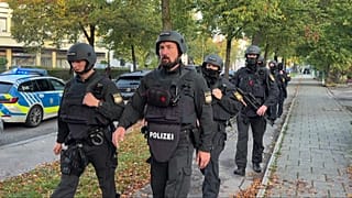 Police officers walk along a footpath after a fire in a detached house in Munich, Germany, Wednesday, Oct. 1, 2025