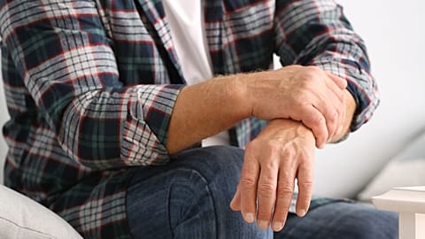 An older man holds his wrist.
