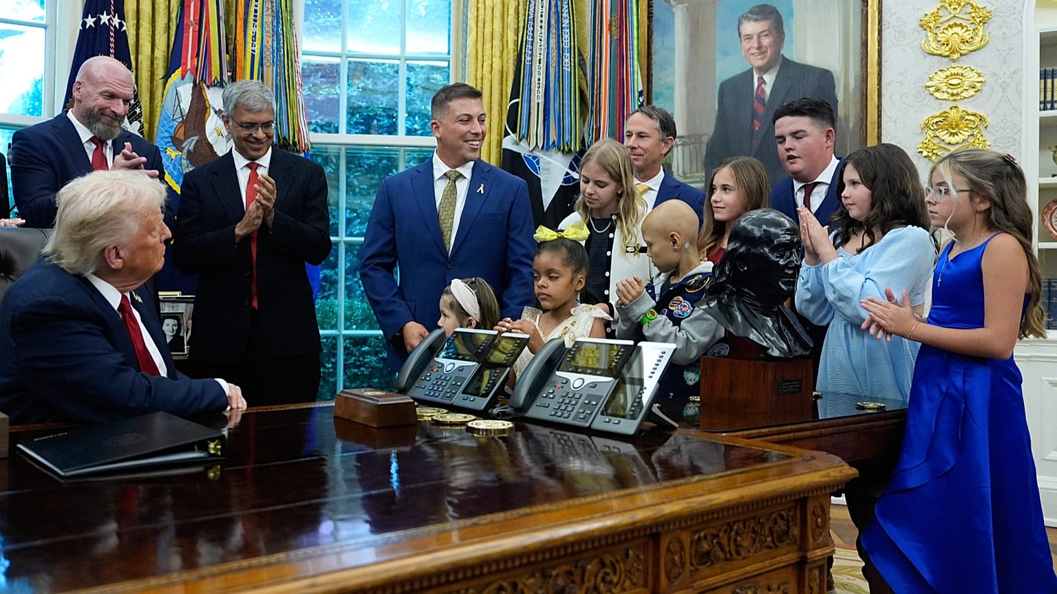 President Donald Trump listens to children who have survived cancer as he speaks in the Oval Office of the White House. 