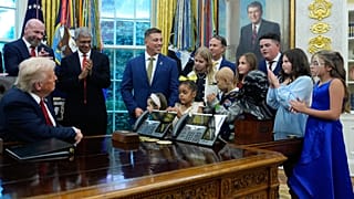 President Donald Trump listens to children who have survived cancer as he speaks in the Oval Office of the White House. 