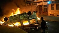 A boy stands next to a torched police vehicle as youth led protests calling for healthcare and education reforms turned violent, in Sale, Morocco, Wednesday, Oct. 1, 2025.