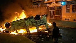 A boy stands next to a torched police vehicle as youth led protests calling for healthcare and education reforms turned violent, in Sale, Morocco, Wednesday, Oct. 1, 2025.
