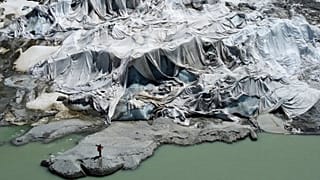  Matthias Huss, of the Federal Institute of Technology in Zurich and glacier monitoring group GLAMOS, stands at the Rhone Glacier that is partially covered with sheets.