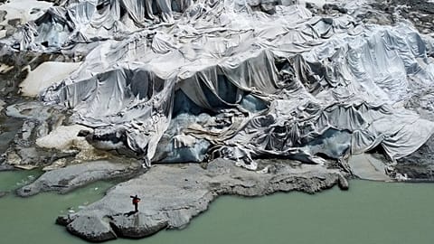  Matthias Huss, of the Federal Institute of Technology in Zurich and glacier monitoring group GLAMOS, stands at the Rhone Glacier that is partially covered with sheets.