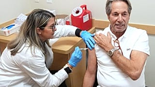 Daniel Toccin recebe uma vacina contra a COVID-19 enquanto ele e a sua mulher se vacinam contra o coronavírus e a gripe sazonal para uma próxima viagem em Miami, 9 de setembro de 2025.