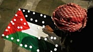 Mulher coloca velas em cima de uma bandeira palestiniana em Roma