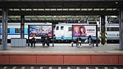 Választási plakátok alatt ülő, metróra várakozó emberek Prágában, 2025. szeptember 26-án