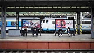 Választási plakátok alatt ülő, metróra várakozó emberek Prágában, 2025. szeptember 26-án