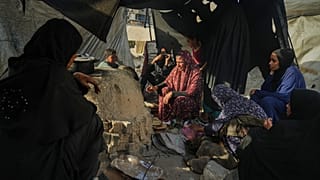 نساء فلسطينيات يخبزن الخبز في فرن طيني، باستخدام البلاستيك للنار، في مدرسة تابعة للأمم المتحدة تُستخدم كمأوى للفلسطينيين النازحين في خان يونس، الأحد 5 أكتوبر/تشرين الأول 2025.