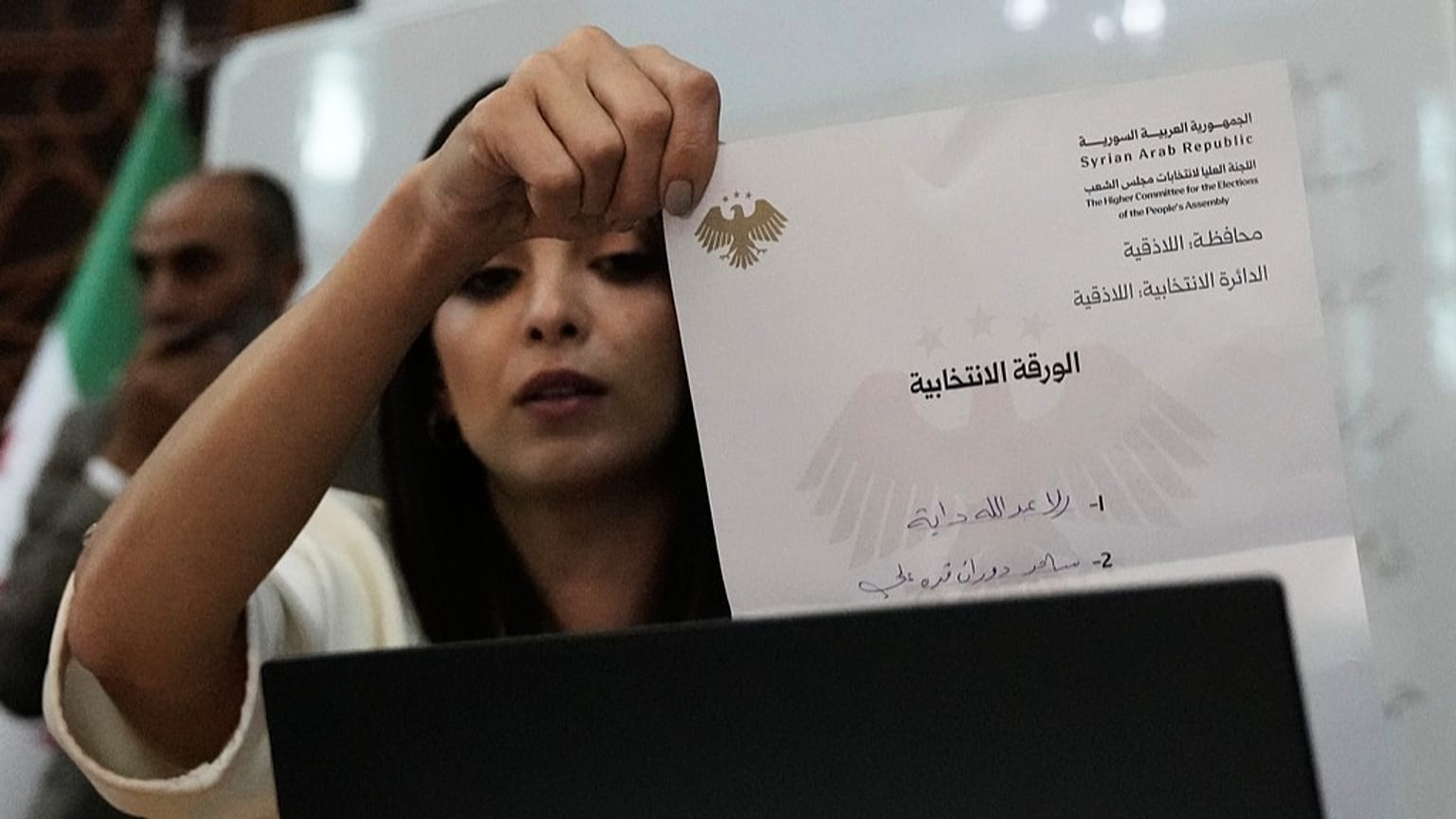 A Syrian election official shows a ballot paper during the counting of ballots, shortly after polling stations closed at Latakia's Governor building, Sunday, Oct. 5, 2025
