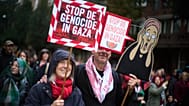 Two people with signs reading "Stop the Genocide in Gaza"