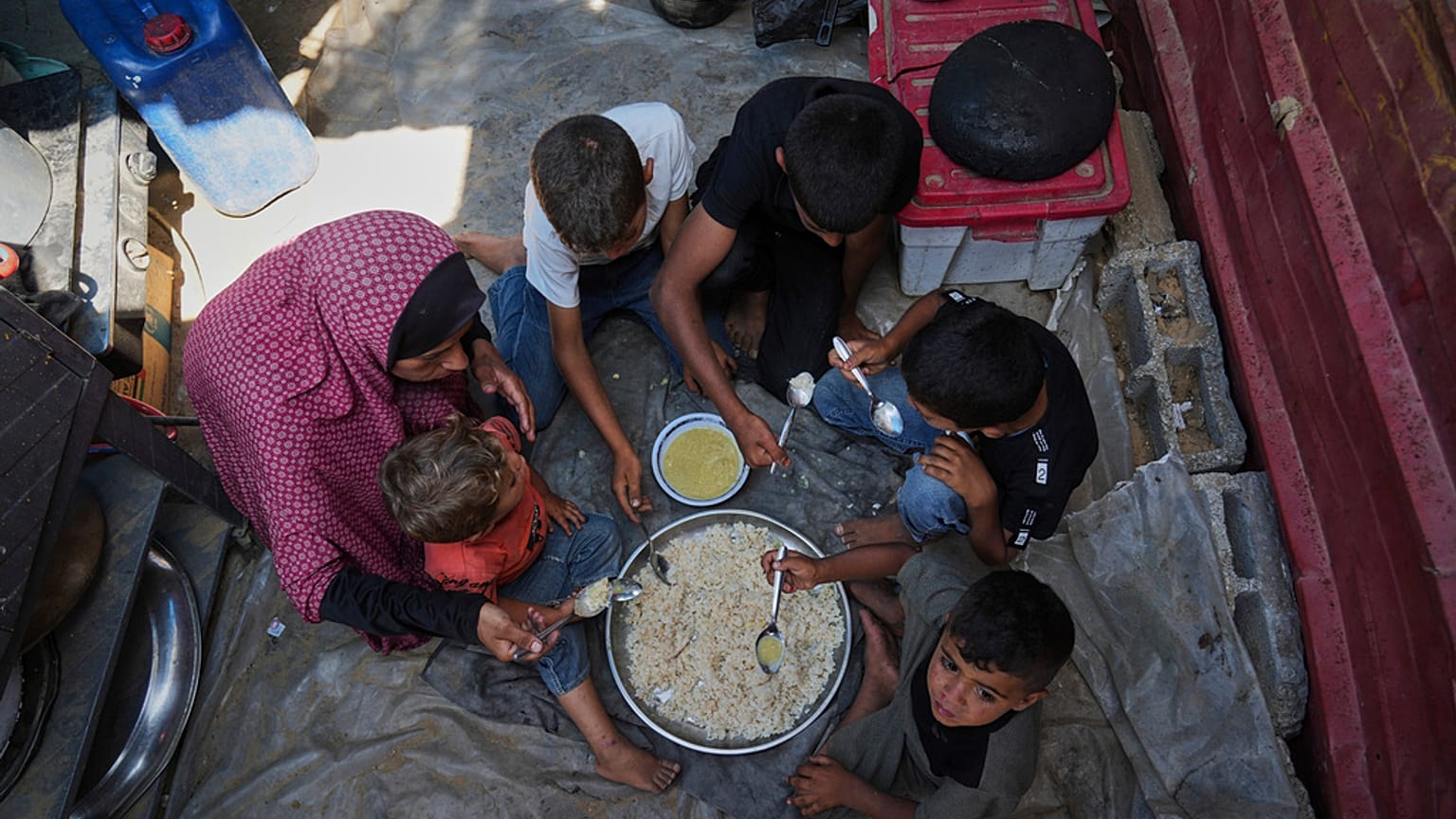 سيدة فلسطينية تشارك أطفالها وجبة داخل خيمتهم في مخيم للنازحين الفلسطينيين في مواصي خان يونس، قطاع غزة، يوم الجمعة 6 يونيو 2025.