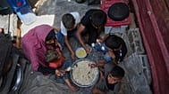 سيدة فلسطينية تشارك أطفالها وجبة داخل خيمتهم في مخيم للنازحين الفلسطينيين في مواصي خان يونس، قطاع غزة، يوم الجمعة 6 يونيو 2025.