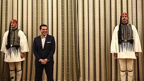 FILE: Greece's Alexis Tsipras smiles as he stands between Presidential Guards during a swearing in ceremony at the Presidential palace in Athens, 5 October 2016